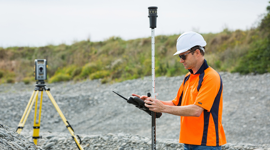 Construction worker using Trimble Controller with EM120 Empower radio module and robotic total station onsite