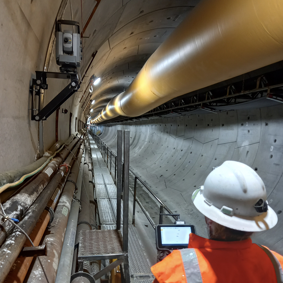 Worker in high-visibility vest using Trimble S9 Total Station in a tunnel