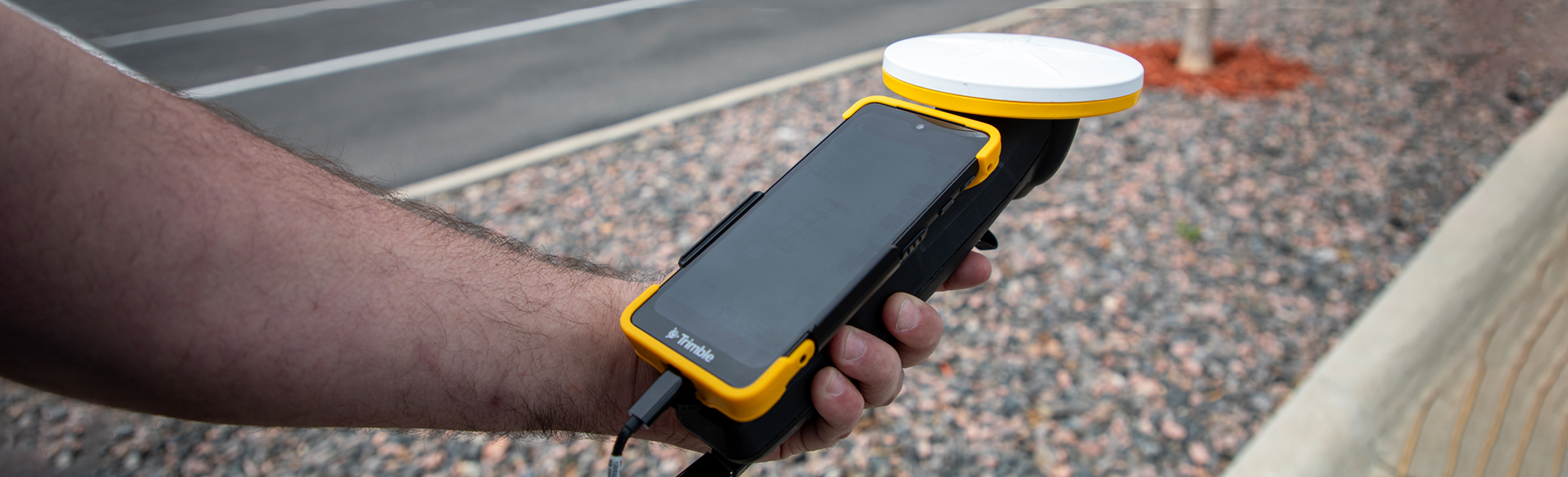 Man holding a handheld mapper with a vehicle collision in the background