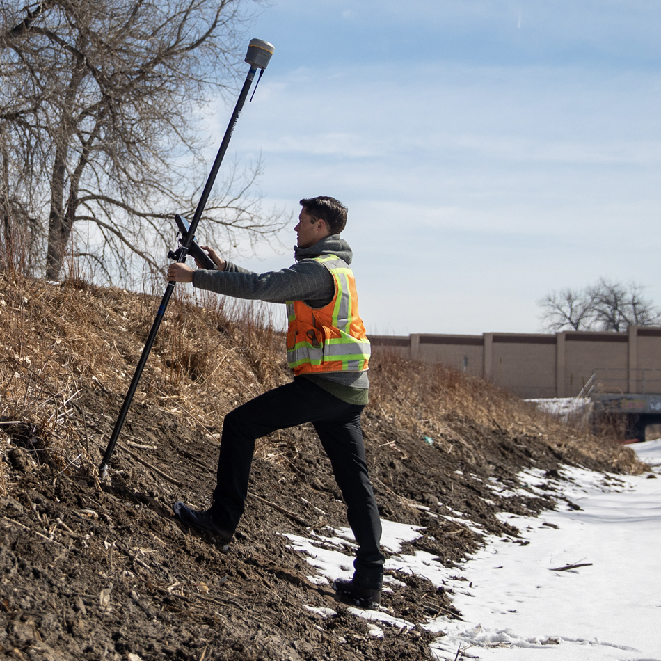 Topógrafo con chaleco de alta visibilidad usando un sistema Trimble R12i GNSS