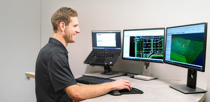 Multiple desktop monitors displaying Trimble Business Center software in an construction office