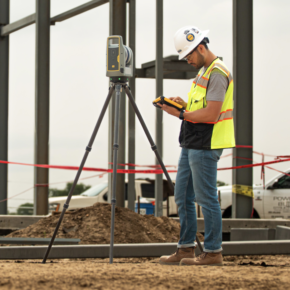 Worker in vest and hard hat using Trimble X9 Laser Scanner at a building construction site