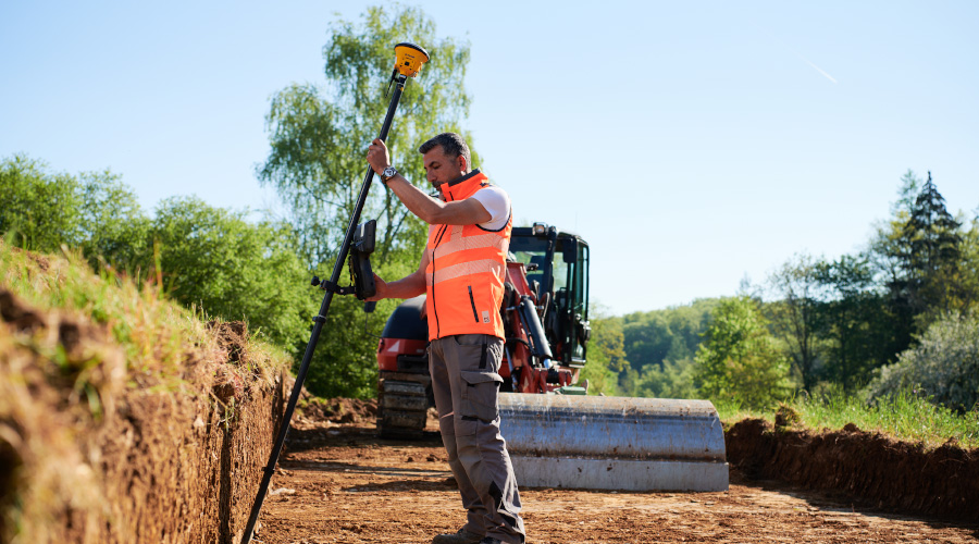 Construction worker using Trimble Siteworks Machine Guidance surveying tools on excavator in-cab display for grade control