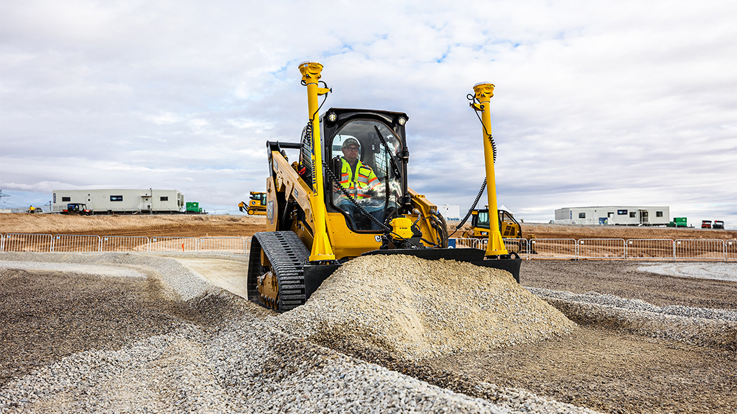 Trimble Earthworks in use on a Compact Track Loader with grading attachments, moving gravel on a construction site