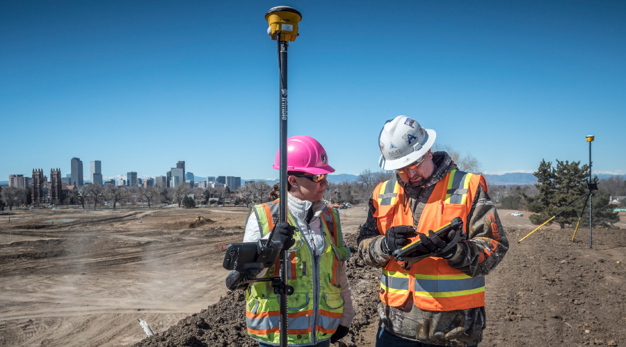 Two construction workers using a trimble antenna 