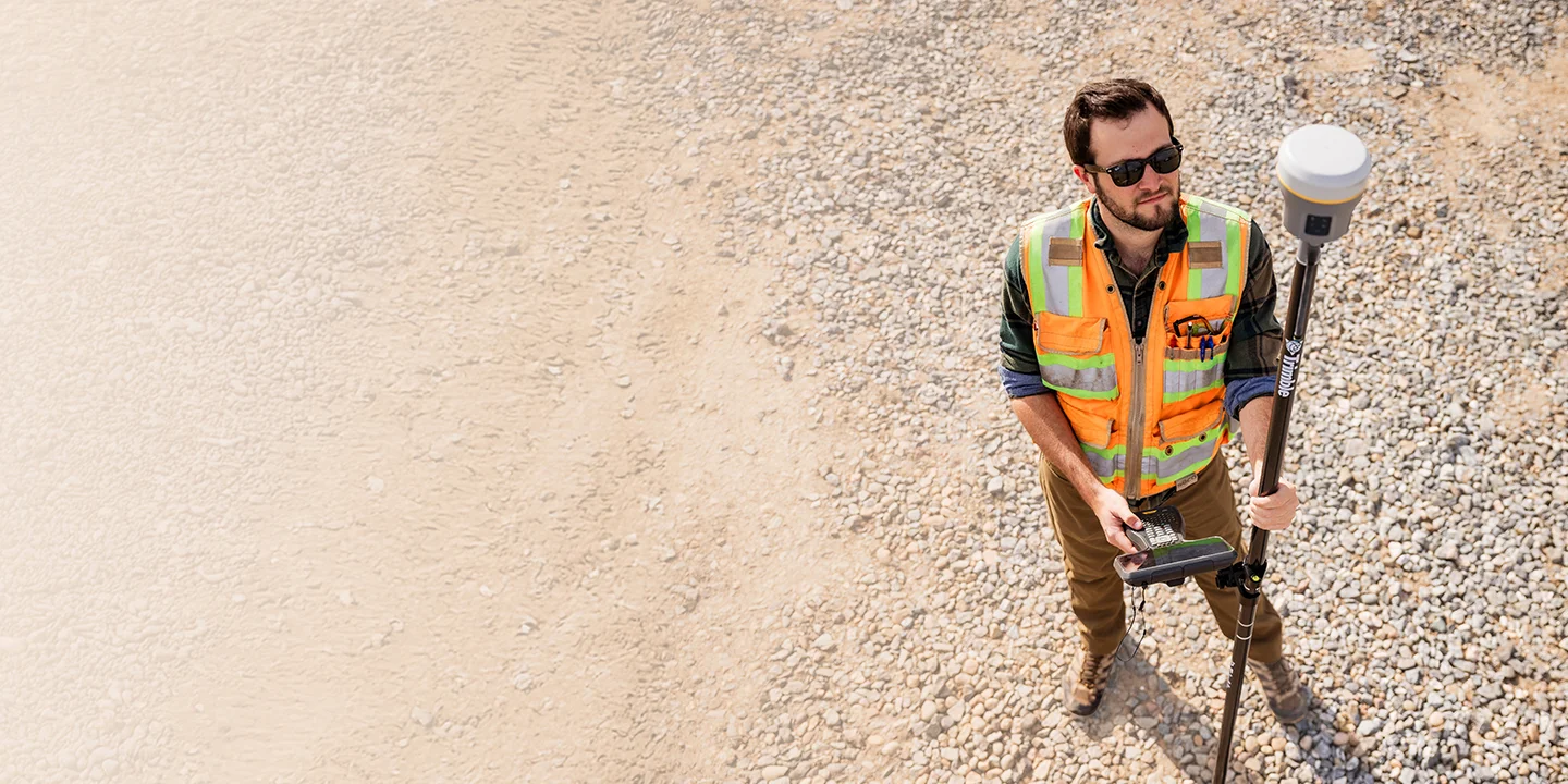 Surveyor in the field using GNSS surveying technology on a Trimble Works subscription.