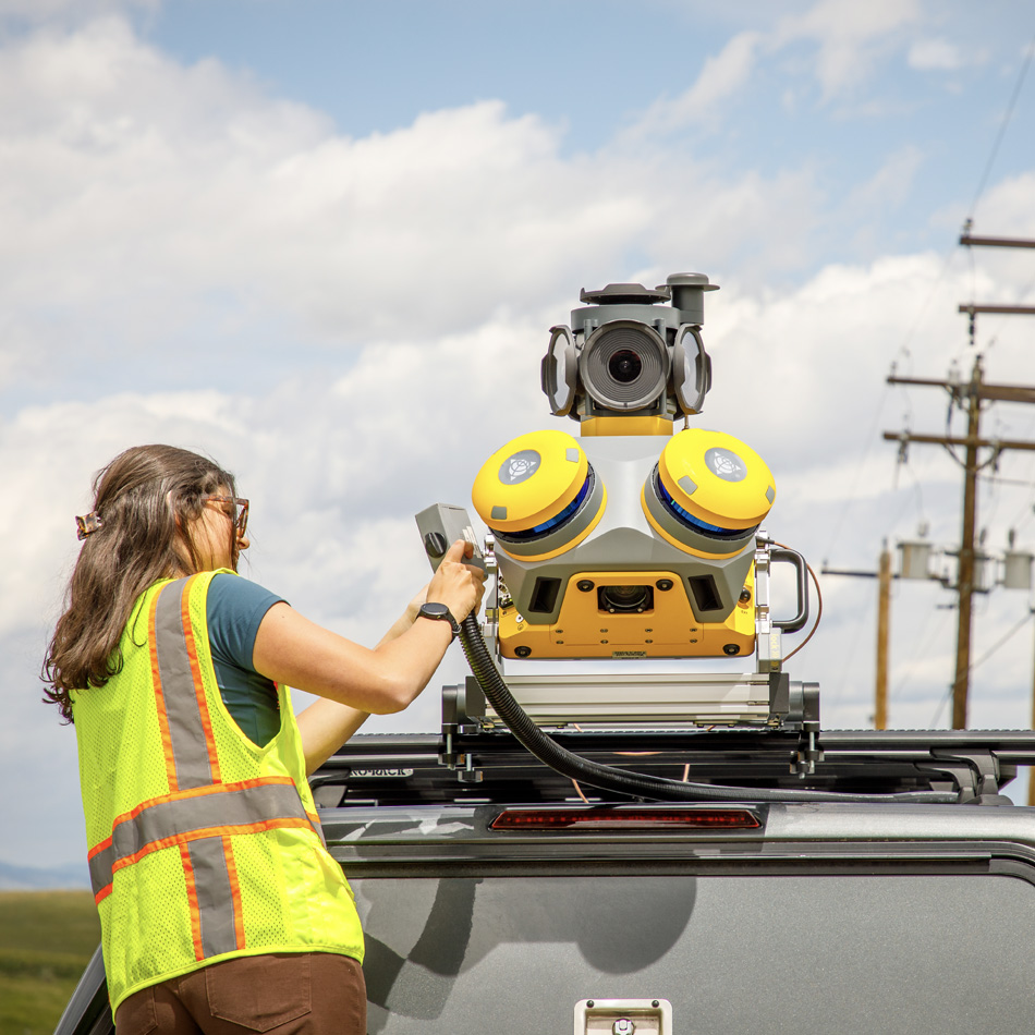 Topógrafo con chaleco de alta visibilidad montando un sistema de mapeo móvil Trimble MX60 en un vehículo