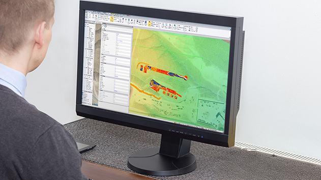 Desktop monitor displaying a Trimble Business Center software model and the design features