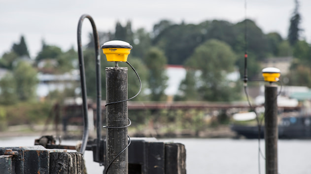 Trimble Internet Base Station Service (IBSS) marine survey equipment in a boat cabin overlooking a port