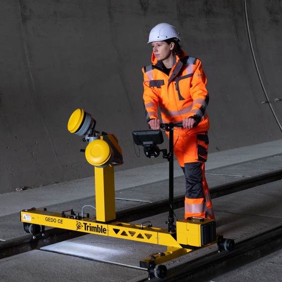 Une femme utilise le chariot de mesure Trimble GEDO CE pour mesurer une voie ferrée