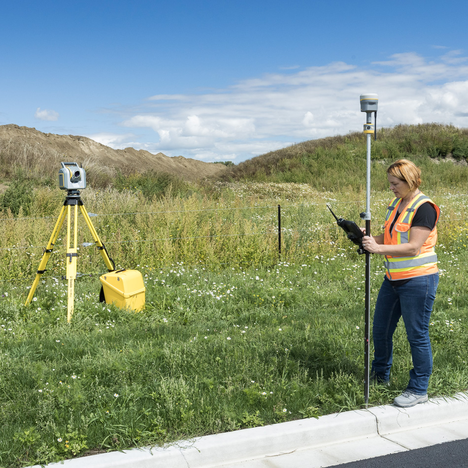 一名测绘人员在道路旁侧操作 Trimble R980 GNSS 和 SX12 全站仪