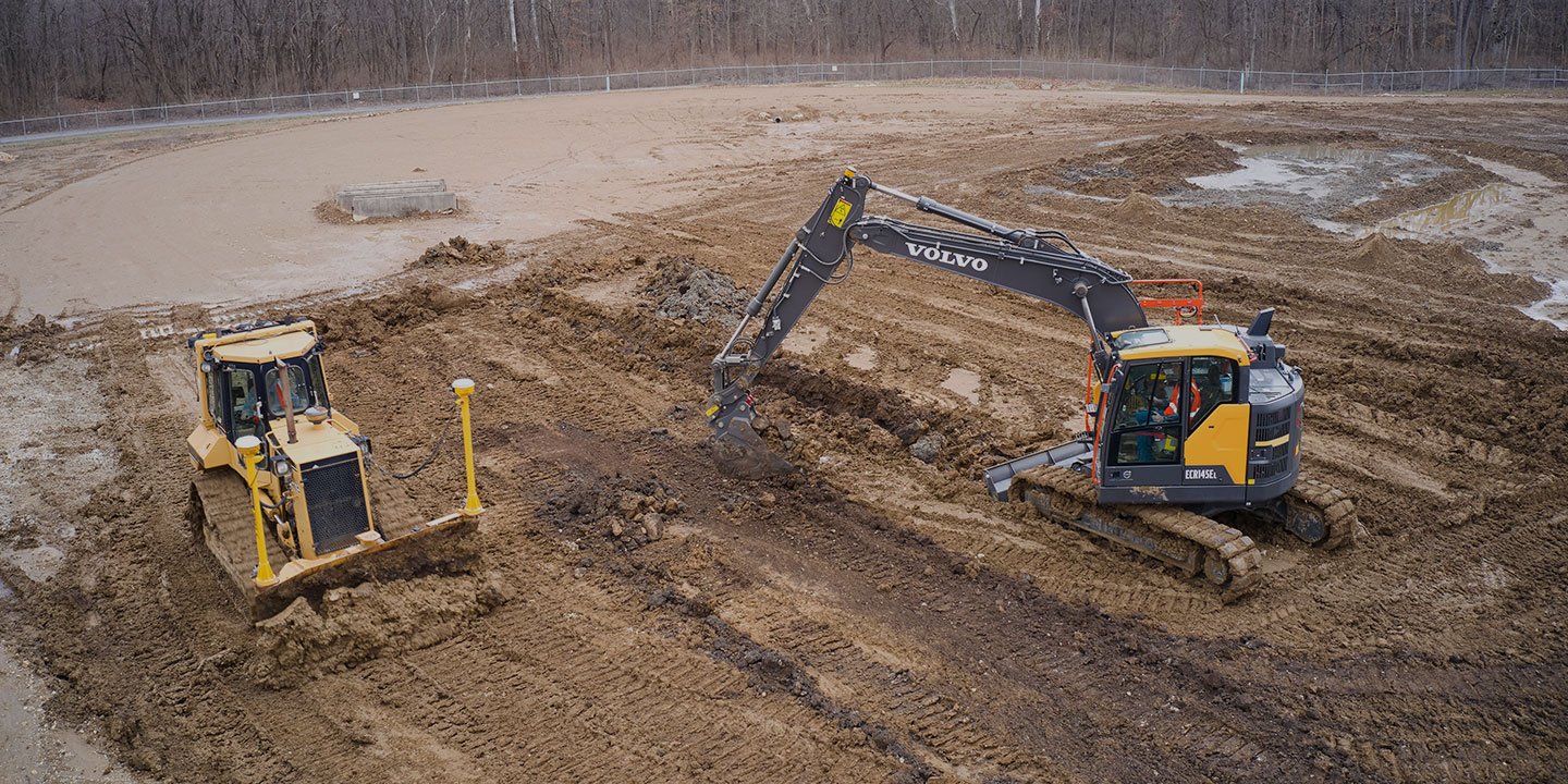 Large excavator and bulldozer managing grade control in a gravel pit