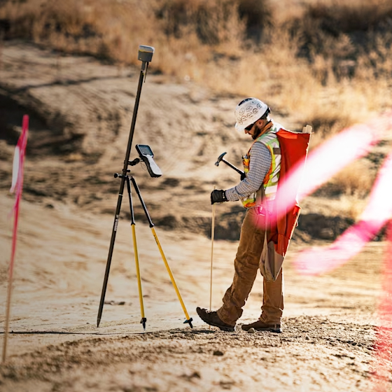 Surveyor using Trimble R12i GNSS system and TSC7 tablet to stakeout a construction project