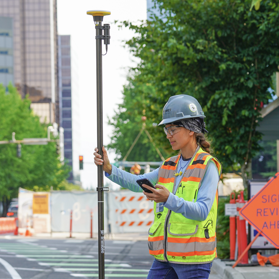 Vermessungsingenieur in Warnweste verwendet Trimble Catalyst mit DA2-Empfänger