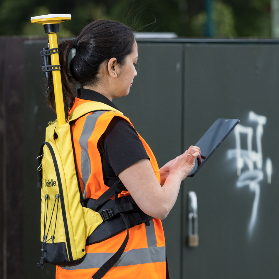 Topógrafo con chaleco de alta visibilidad utilizando Trimble Catalyst con un receptor DA2