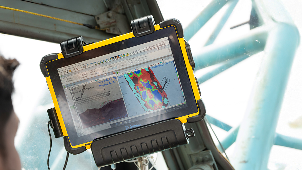 Marine construction worker using Trimble marine construction software in a cab