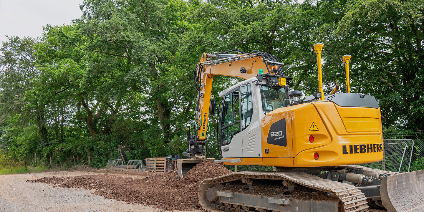 Compact excavator using trimble antennas to dig a trench