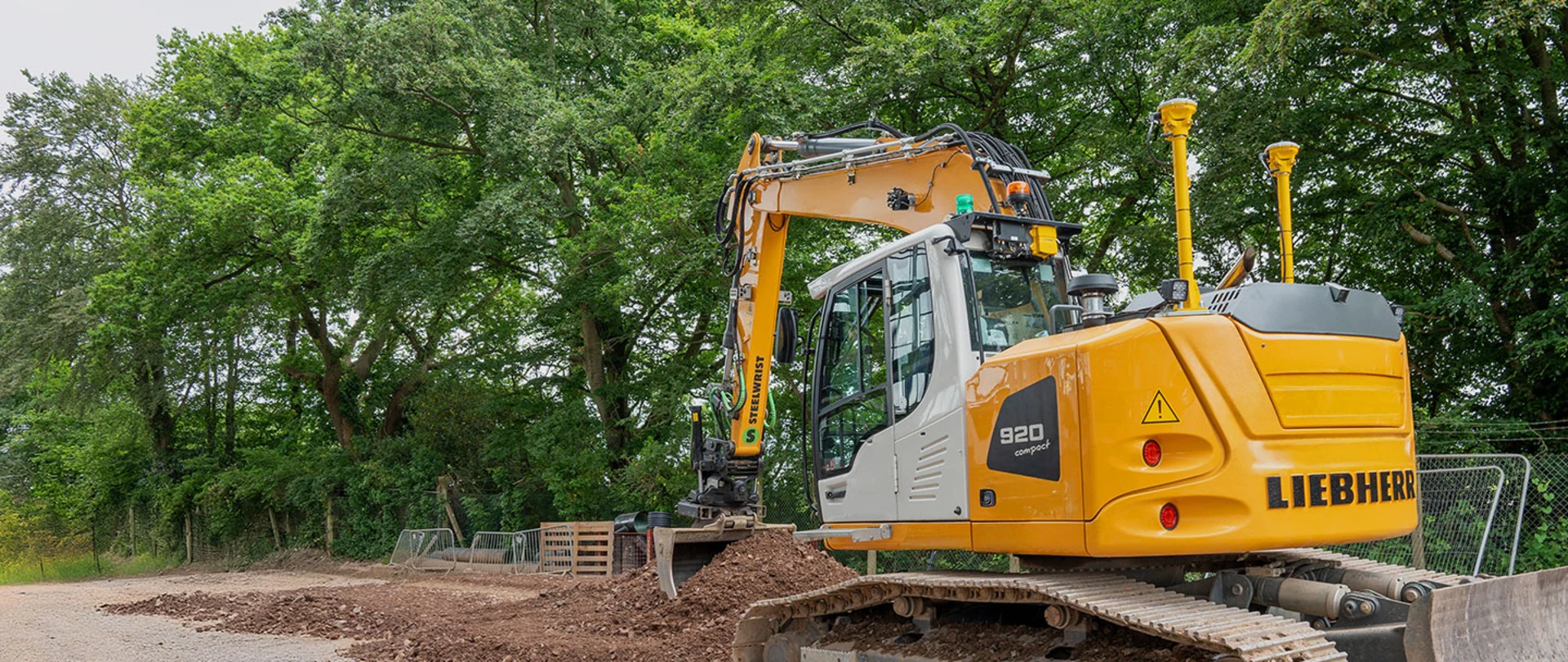 Compact excavator using trimble antennas to dig a trench