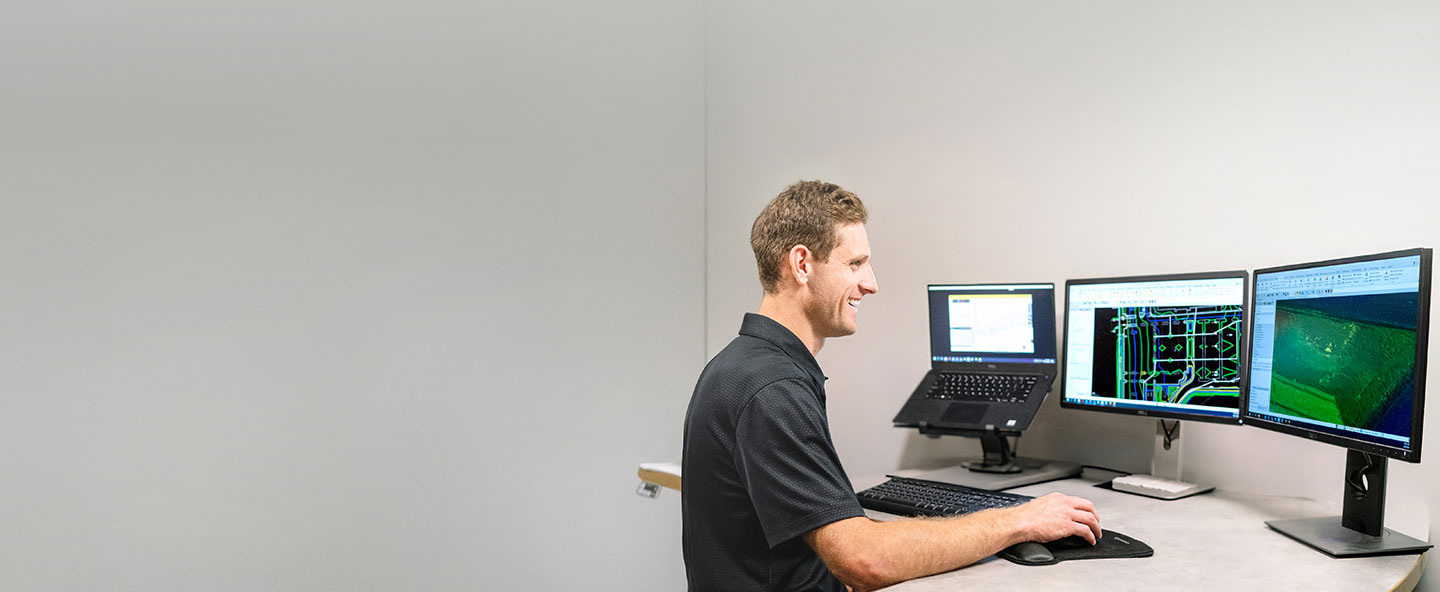 Multiple desktop monitors displaying Trimble Business Center software in a construction office