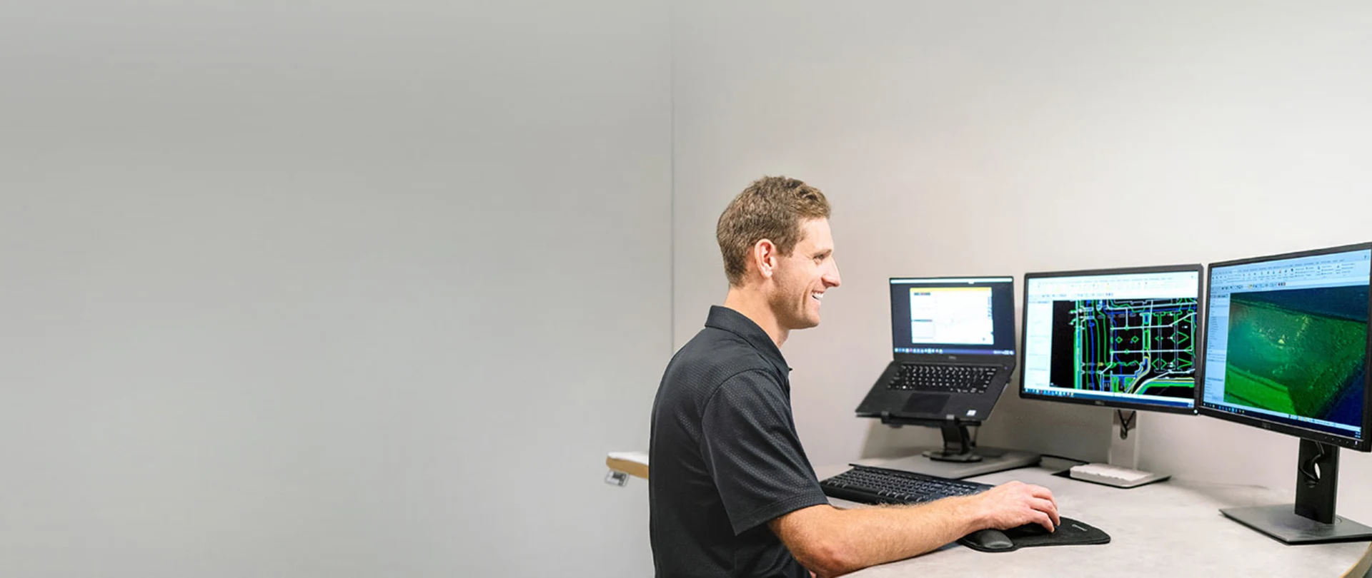 Multiple desktop monitors displaying Trimble Business Center software in a construction office