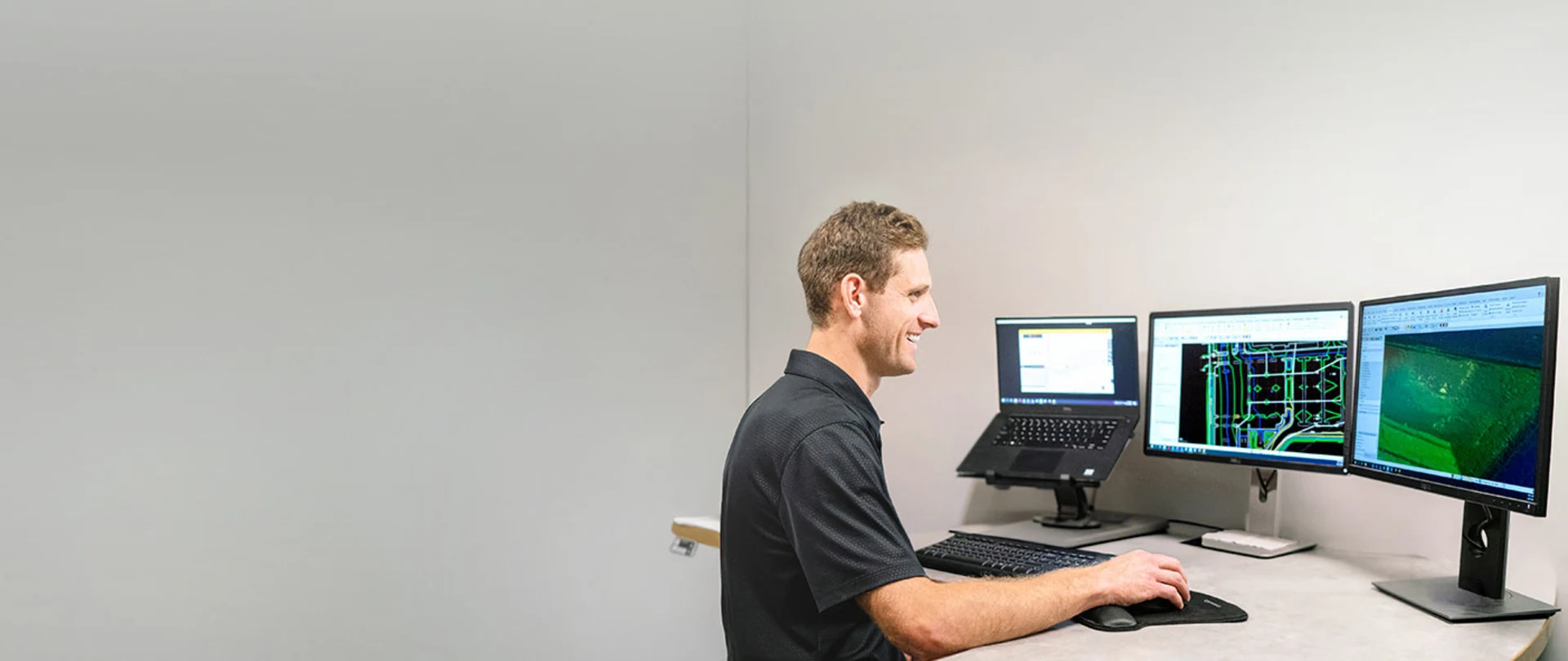 Multiple desktop monitors displaying Trimble Business Center software in a construction office