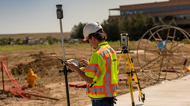 Surveyor using a Trimble T110 tablet on a construction site