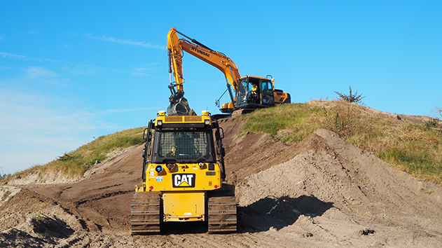 An excavator working on a hill alongside a dozer, using Trimble Earthworks 3D Machine Control technology
