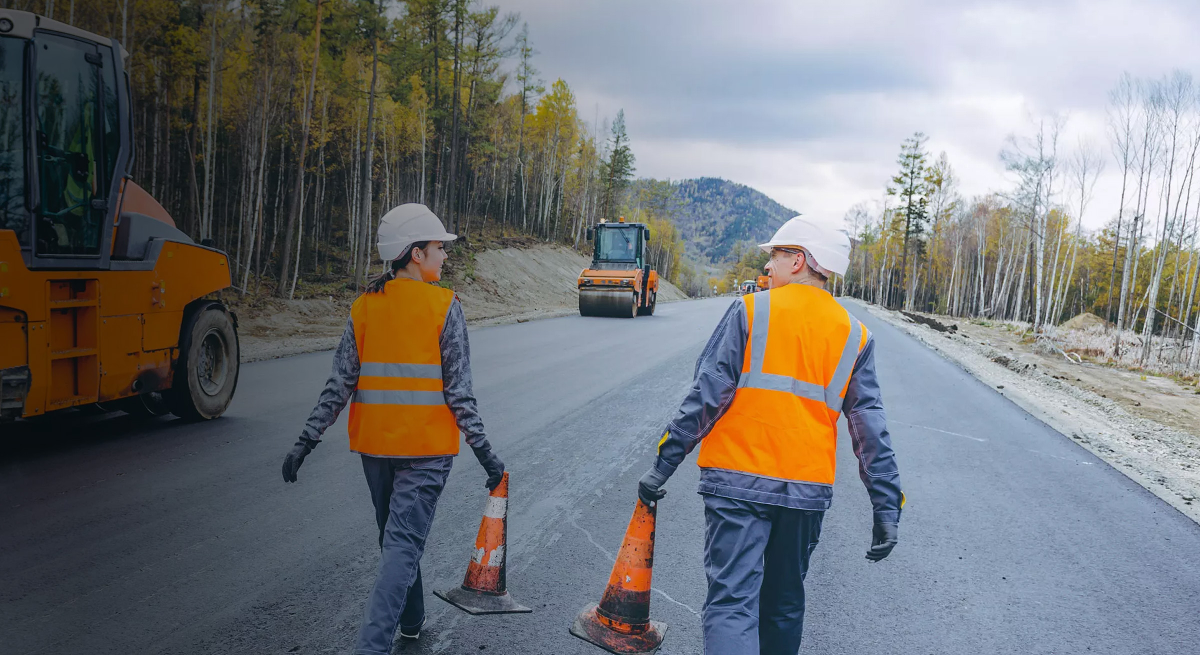 Two workers walking next to pavers