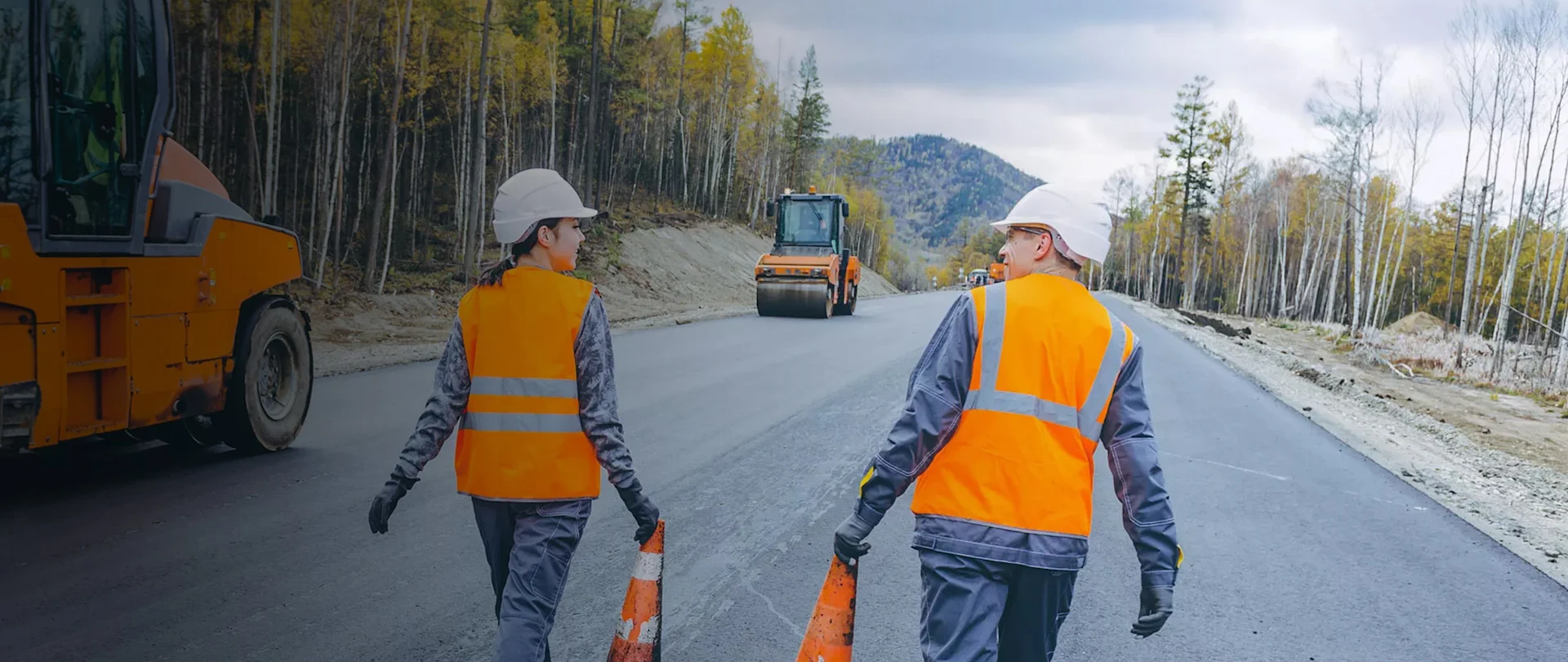 Two workers walking next to pavers