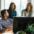 Three people work together while looking at a computer screen.