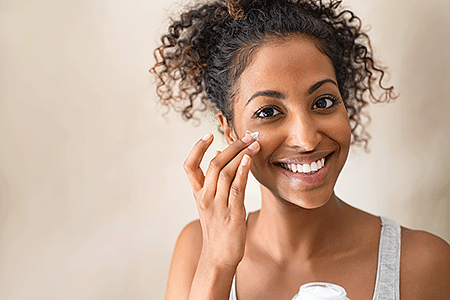 Woman applying moisturizer to face