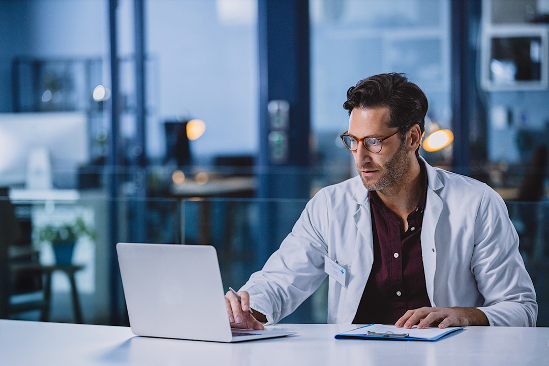 Doctor sitting at a desk watching the AADA Presidential Town Hall.