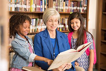 Adult woman reading a book to two young girls