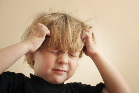 A four year-old boy scratching his head