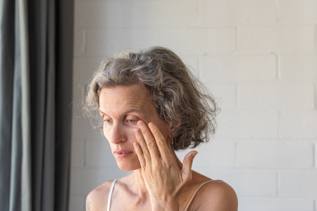 Woman touching her eye for an article about eye problems related to Rosacea.