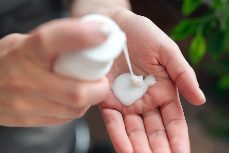 Woman pumping lotion out of a bottle, so she can apply it to pityriasis rosea rash