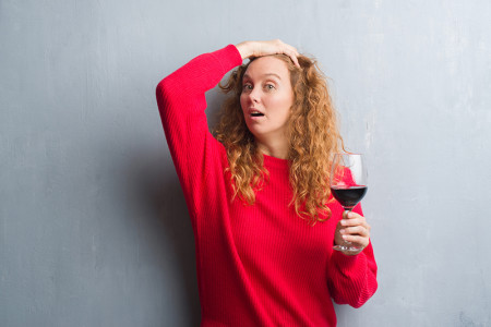 Young woman holding a wine glass in an article about alcohol as a trigger for Rosacea