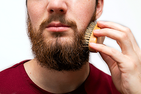 Man gently brushing his beard with a beard brush.