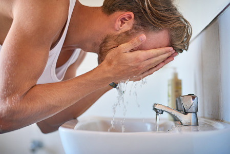 Young man reducing acne by following skin care tips from dermatologist. 