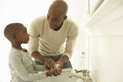 Father and son washing hands with soap in bathroom sink