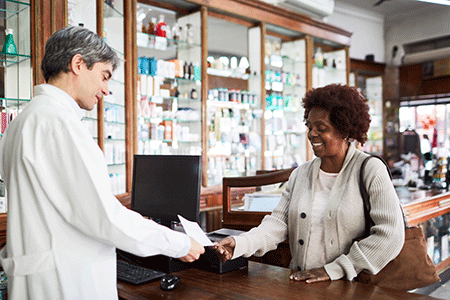 Pharmacist handing woman a prescription medication