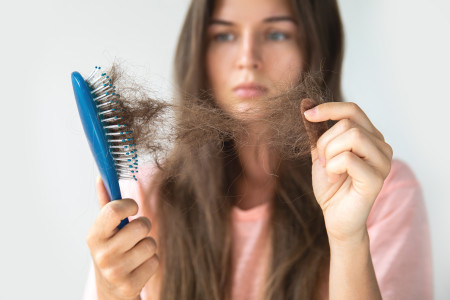 زن در حال کندن مو از برس