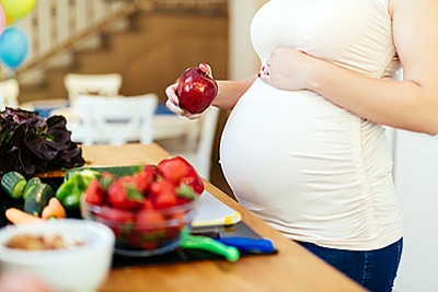 Pregnant woman holding apple