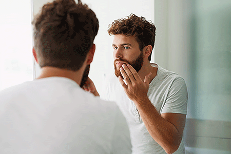 Bearded man checking his skin.