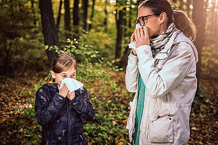 Mother and daughter in forest blowing noses 