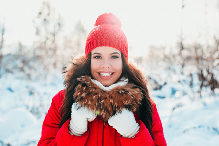 Young woman outdoors in winter dressed with a heavy coat, hat, and gloves