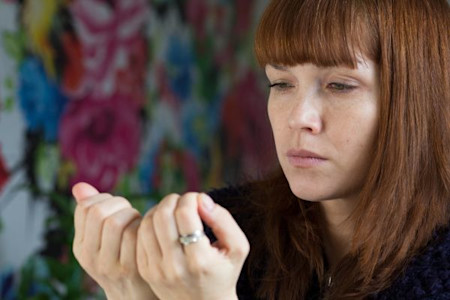 Middle aged woman looking at her nails, displeased