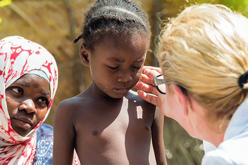 Dermatologist talking with child from underserved country.