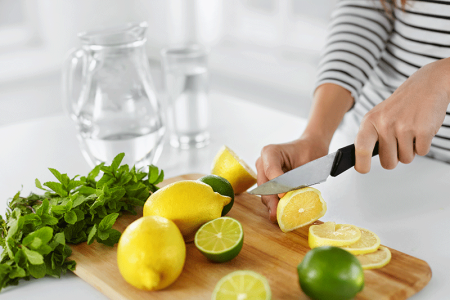 Close-up of woman using a knife to cut lemons and limes