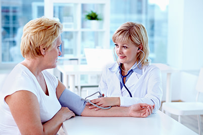 Female physician taking blood pressure of female patient.